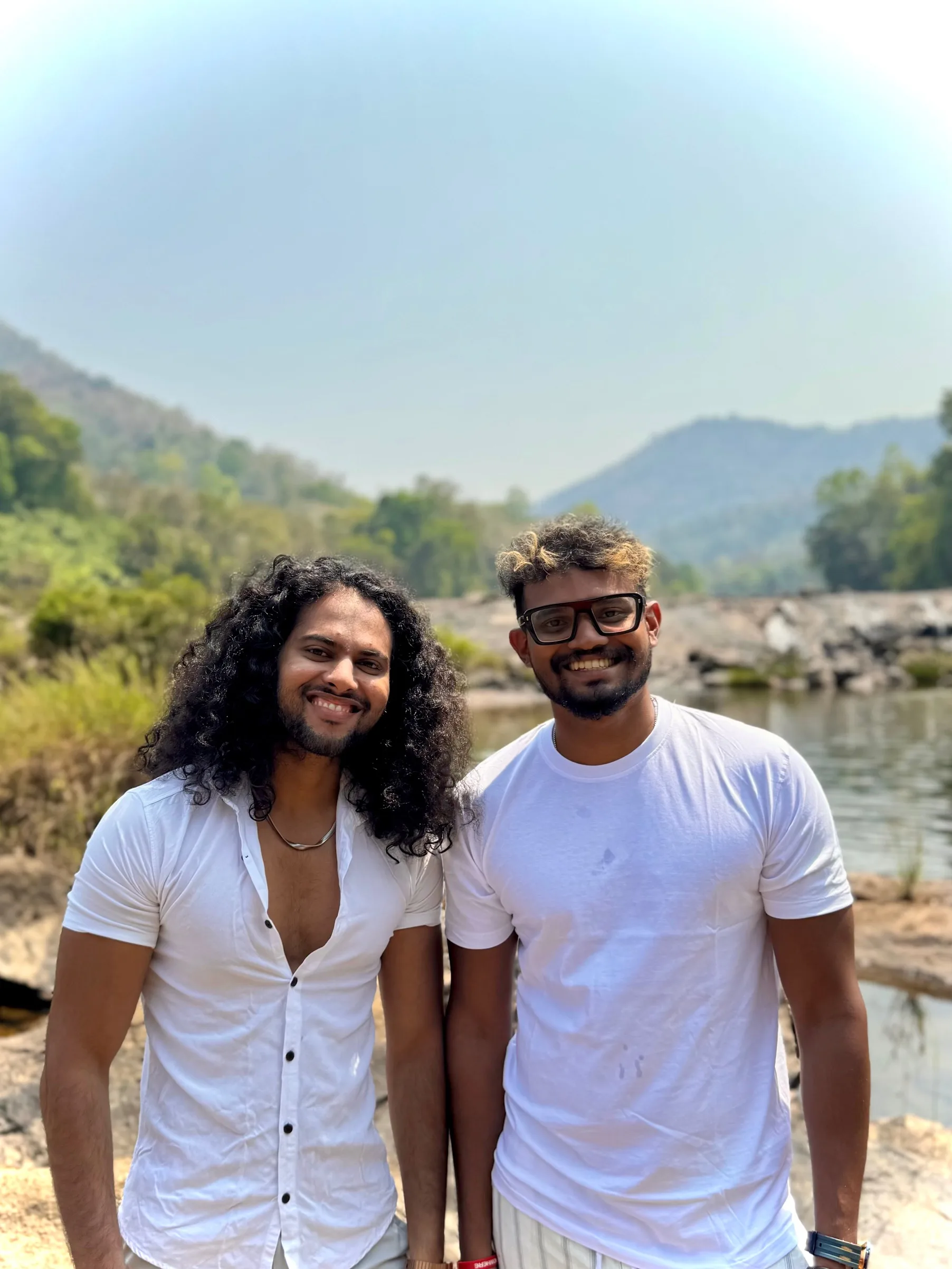 Achu and Nithin, the founders of Samya Retreats, smiling by a river in Kerala