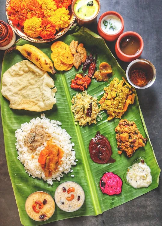 A Kerala meal served on a banana leaf with rice, curries, pickles and papadam