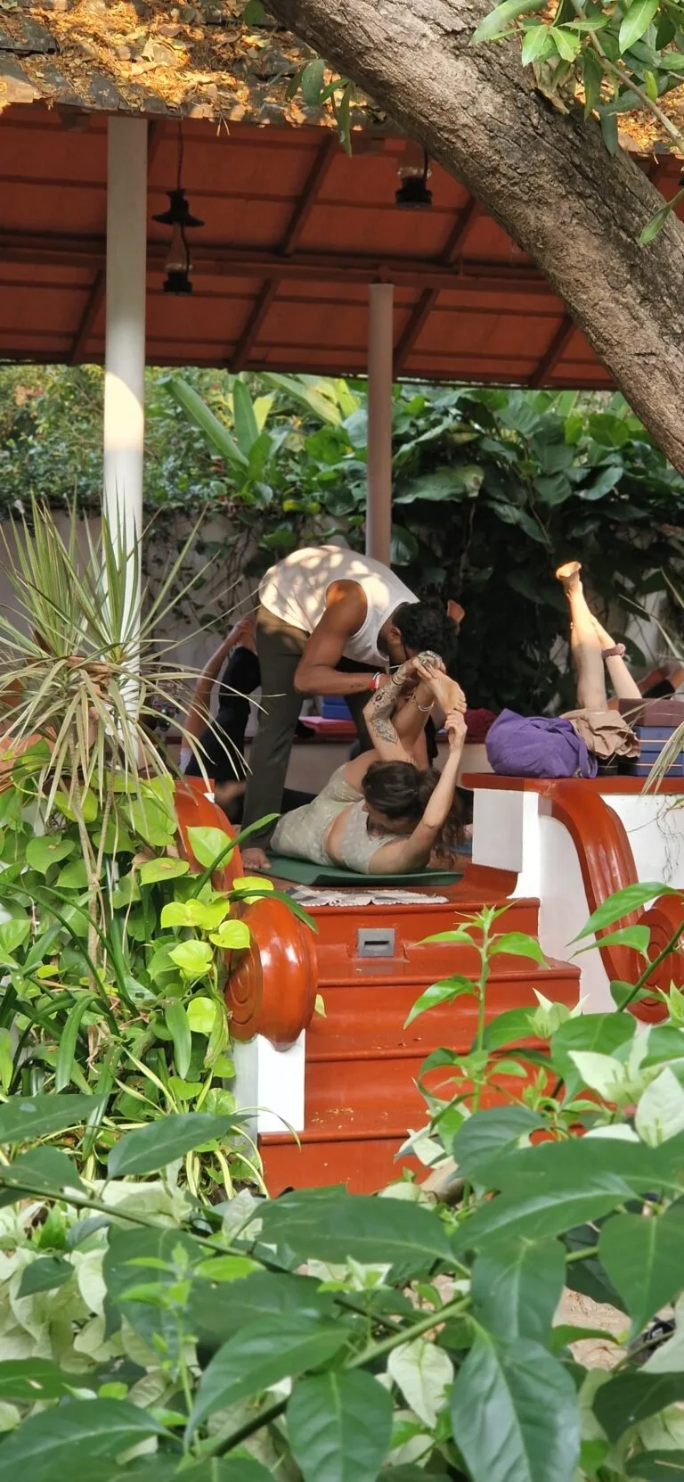 Guests practising yoga in an open-sided shala surrounded by plants